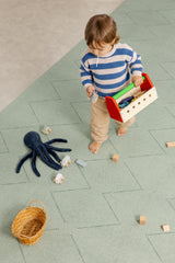Child playing with wooden toys on the Toddlekind Tulum Agave Playmat in a calming sage green color.