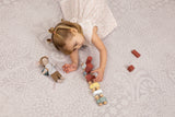 Child playing with wooden blocks on the Toddlekind Aria Maple Playmat, featuring a soft neutral jacquard pattern