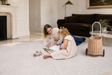 Parent and child drawing together on the Toddlekind Aria Maple Playmat in a bright living room, showcasing the spacious cushioned play surface.