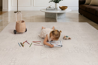 Child drawing on the Toddlekind Aria Playmat with colored pencils, featuring an elegant neutral  design perfect for family living spaces.