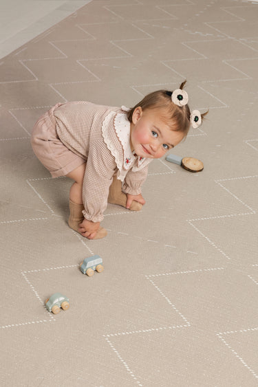 toddler playing with toy cars on the cushioned haven mat tulum desert caliza