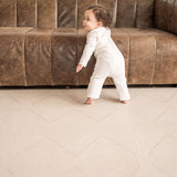 Toddler walking near a sofa on the toddlekind baby toddler foam modern designer puzzle play mat haven tulum bone.
