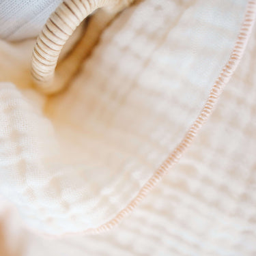 Close-up of toddlekind 3 layer cotton muslin baby blanket kind cloth blush showing breathable textured fabric and stitching.
