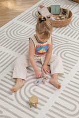 A child sits on the Toddlekind Haven Playmat in Linear Putty, playing with a soft toy. The cushioned foam play mat features a modern geometric pattern, creating a comfortable and stylish space for everyday play.
