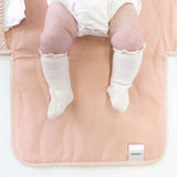 Close-up of baby legs on toddlekind baby portable changing clutch mini maven blush with soft padded surface.

