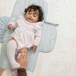 Baby lying on toddlekind baby portable changing clutch mini maven slate with soft cushioned changing surface.
