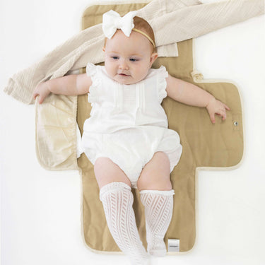 Infant resting on toddlekind baby portable changing clutch mini maven tofu with wings open for comfort and support.
