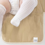 Close-up of baby legs on toddlekind baby portable changing clutch mini maven tofu with soft cushioned surface.
