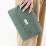 Hand holding folded toddlekind baby portable changing clutch mini maven forest showing compact portable design.
