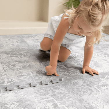 Toddler crawling and playing on soft patterned foam surface, showing comfort and safety of the toddlekind baby toddler foam modern designer puzzle play mat haven parisa pearl blue.
