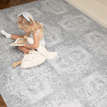 Overhead view of child sitting and reading on a large assembled foam mat, showcasing full coverage of the toddlekind baby toddler foam modern designer puzzle play mat haven parisa pearl blue
