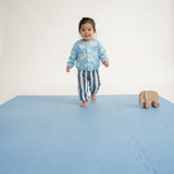 Toddler walking across play area with toy on toddlekind baby toddler foam modern puzzle play mat classic slate.
