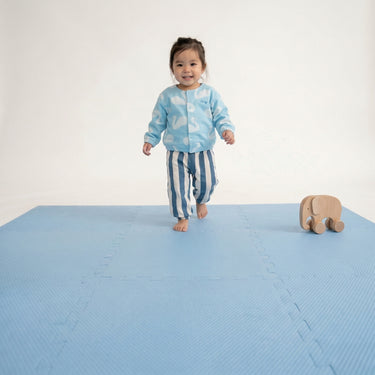 Toddler walking across play area with toy on toddlekind baby toddler foam modern puzzle play mat classic slate.

