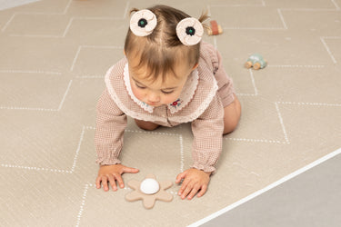 Child playing with a flower toy on the Tulum haven playmat Desert Caliza