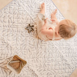 Overhead view of baby playing on soft leaf-pattern mat with bucket and scoop – toddlekind portable water resistant wander classic play mat ocean stone for easy cleanup
