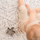 Close-up of baby legs and toy on soft patterned mat – toddlekind portable water resistant wander classic play mat ocean stone with gentle padding
