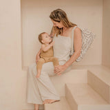 Mother sitting with baby and carrying folded play mat bag – toddlekind portable water resistant wander classic play mat ocean tan for easy transport

