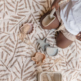 Overhead view of sand toys and child on textured mat surface – toddlekind portable water resistant wander classic play mat ocean tan with easy-clean material
