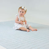 Baby sitting on padded patterned mat indoors – toddlekind portable water resistant wander grande play mat for safe floor play
