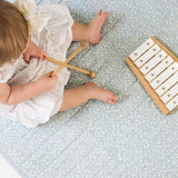 Overhead view of toddler playing with wooden xylophone on quilted mat – toddlekind portable water resistant wander grande play mat for sensory play
