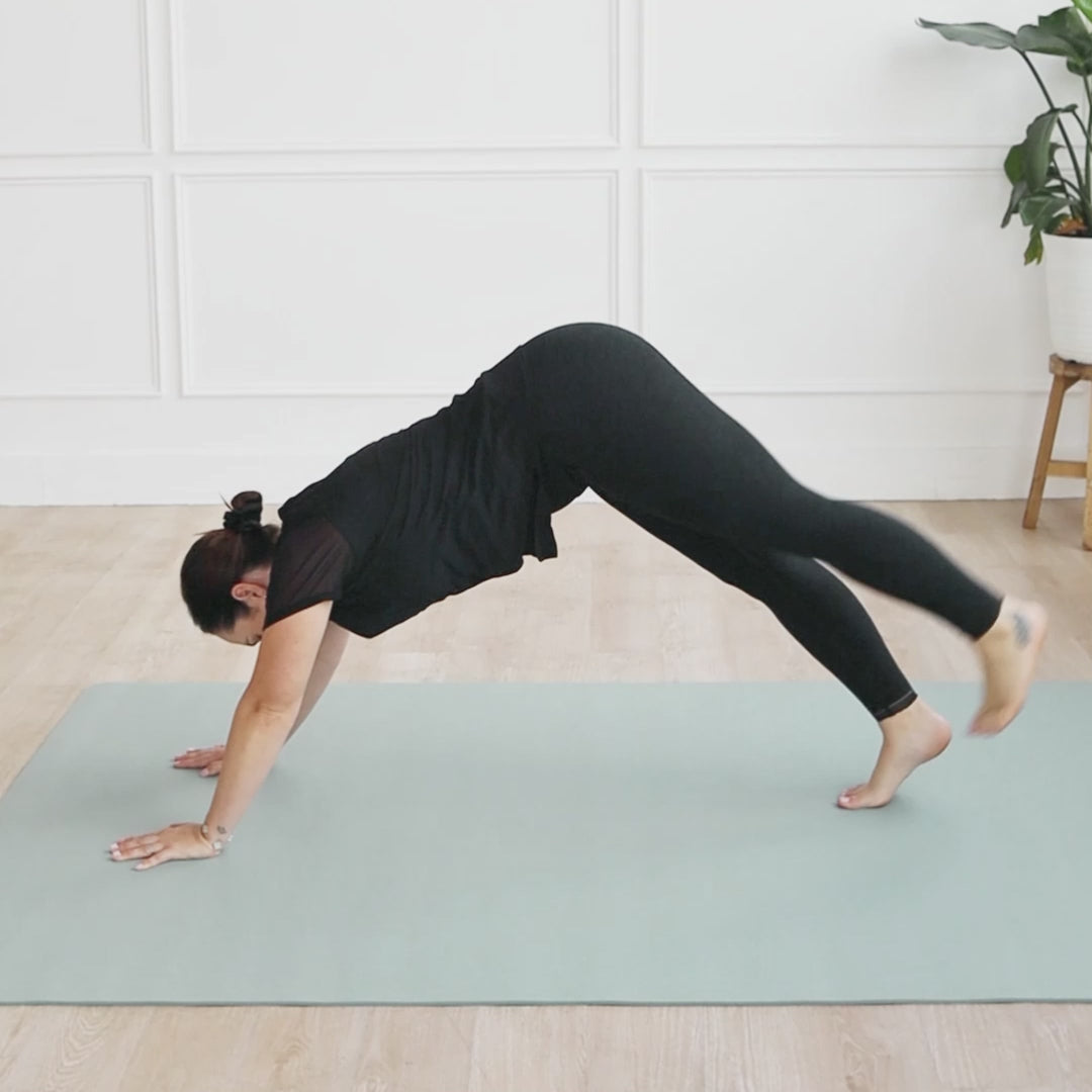 Person practicing yoga on an Evo Mat in sage color, demonstrating a downward dog position.