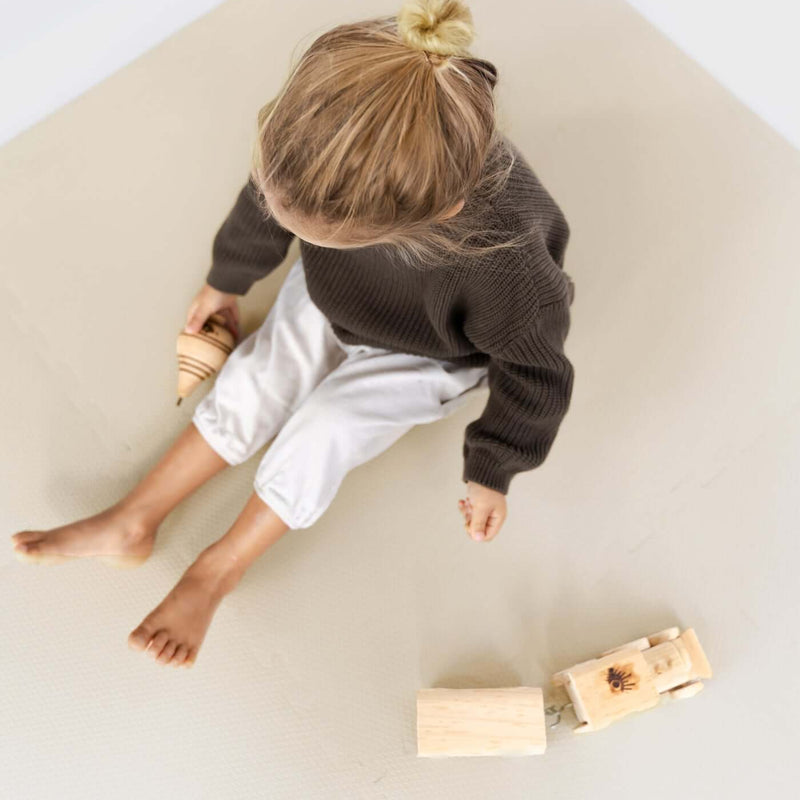 Top view of toddler sitting and playing with wooden toys on toddlekind baby toddler foam modern puzzle play mat classic clay.
