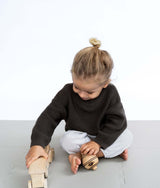 Close-up of toddler pushing wooden train while seated on toddlekind baby toddler foam modern puzzle play mat classic stone.
