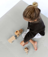 Overhead view of toddler playing with wooden toys on toddlekind baby toddler foam modern puzzle play mat classic stone.

