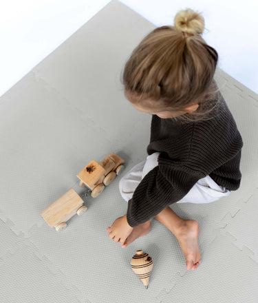 Overhead view of toddler playing with wooden toys on toddlekind baby toddler foam modern puzzle play mat classic stone.
